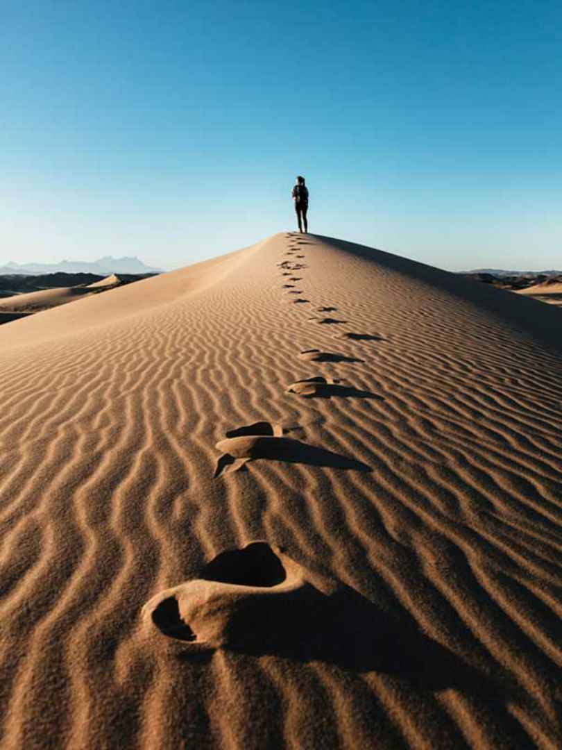 Man standing on a dune in the desert.