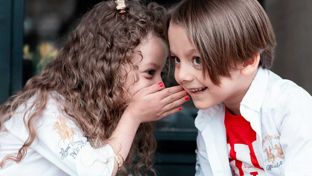 Photo of kids whispering.