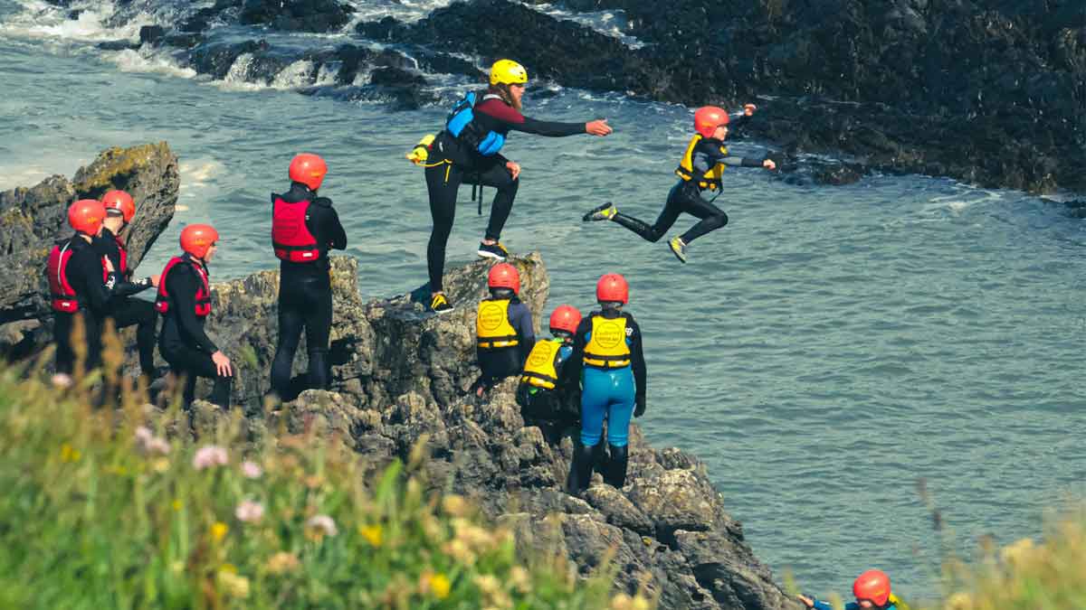Coasteering Image of a girl jumping off a cliff into water.